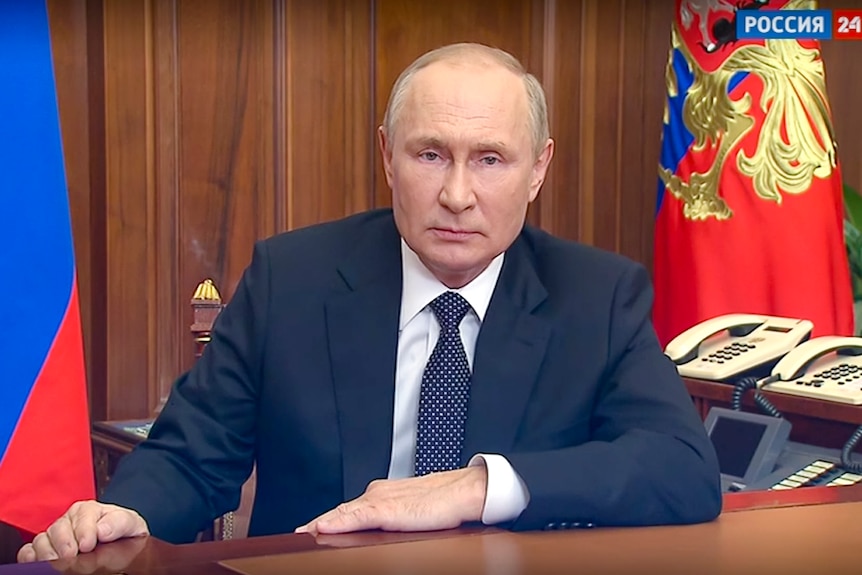 Vladimir Putin sitting at a desk. 
