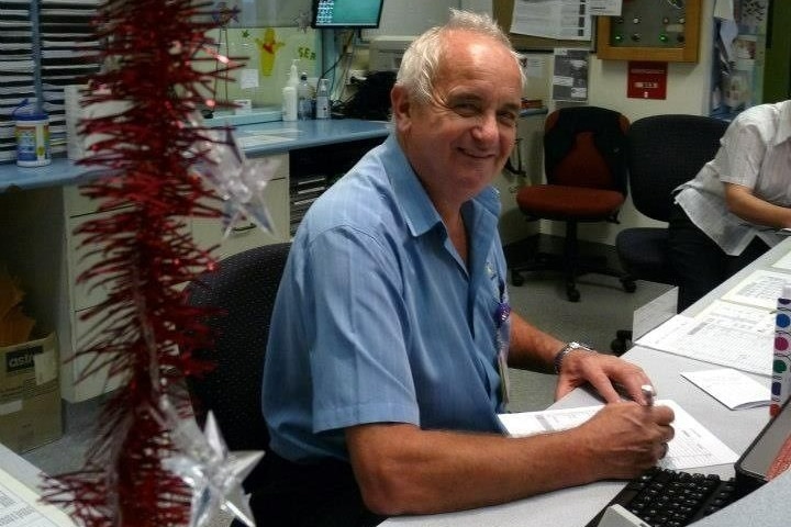 Man sitting behind a counter smiling with paperwork in front of him.