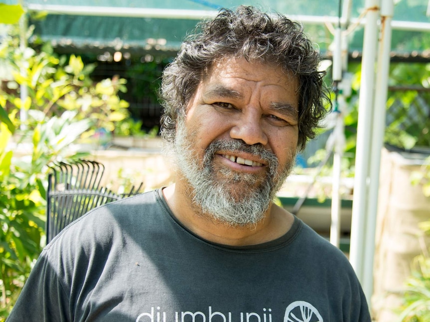 Seith Fourmile stands in his back garden surrounded by native trees and bushfoods.