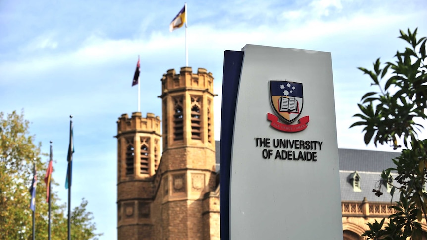 A modern University of Adelaide sign with a 19th century sandstone building behind
