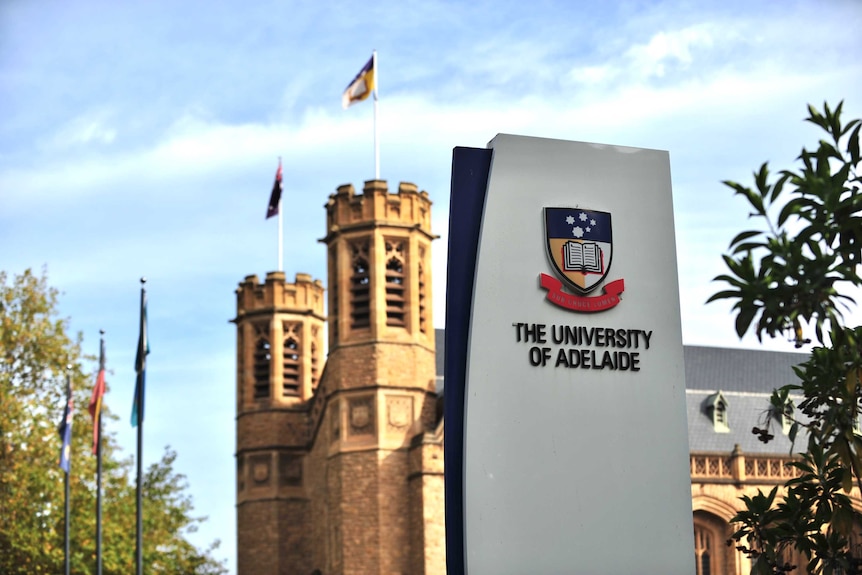 A modern University of Adelaide sign with a 19th century sandstone building behind