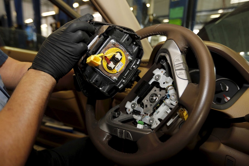 A Takata airbag inflator is removed from a Honda vehicle