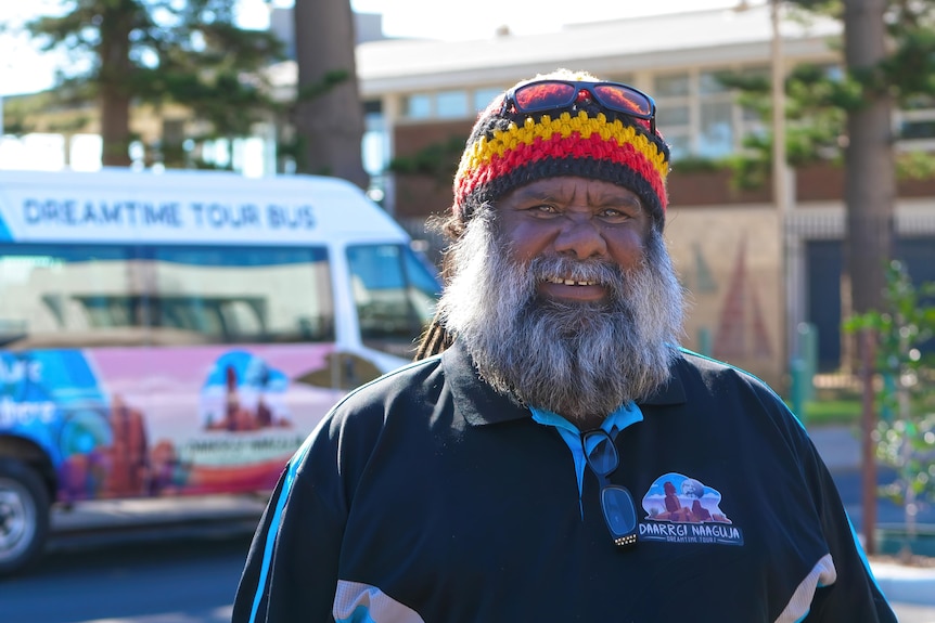 Aboriginal man with beard and beanie smiles at camera