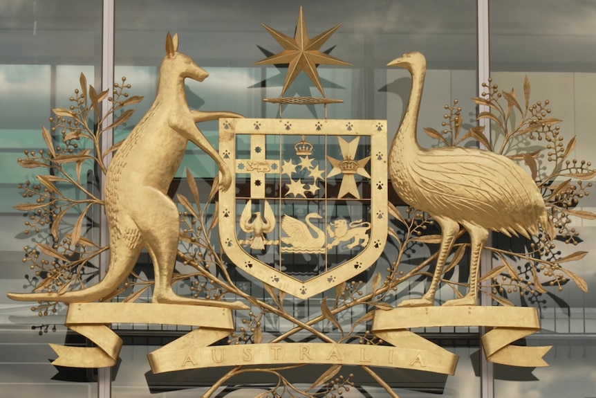 An Australian coat of arms in gold on a building.