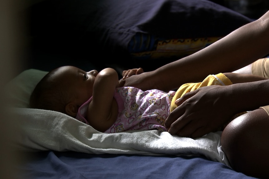 Baby Mohammad lies on a pillow looking up at his mother.