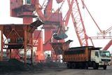Imported coal is seen lifted by cranes from a coal cargo ship onto a truck at a port in China