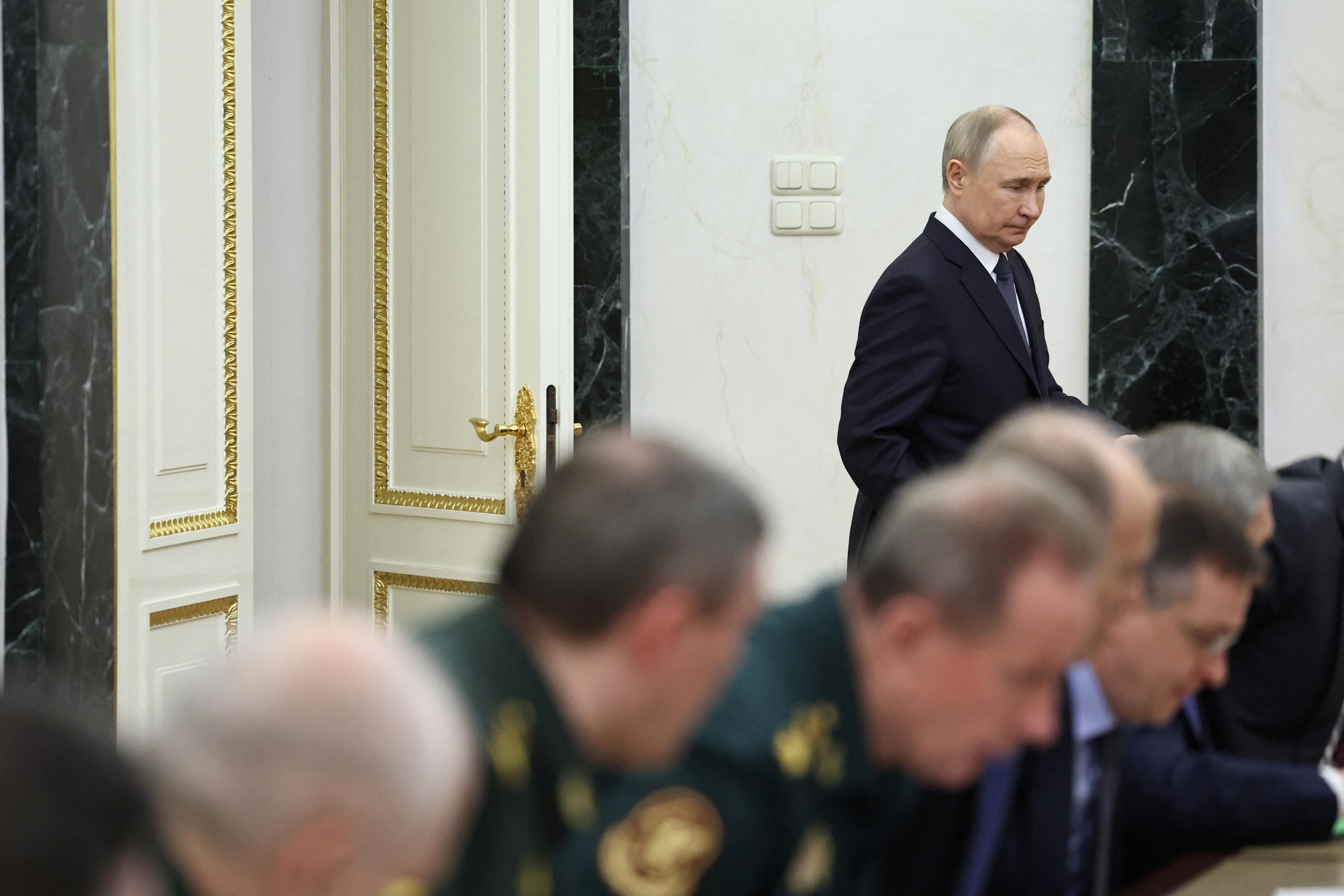 Putin walks to sit at a table with his officials 