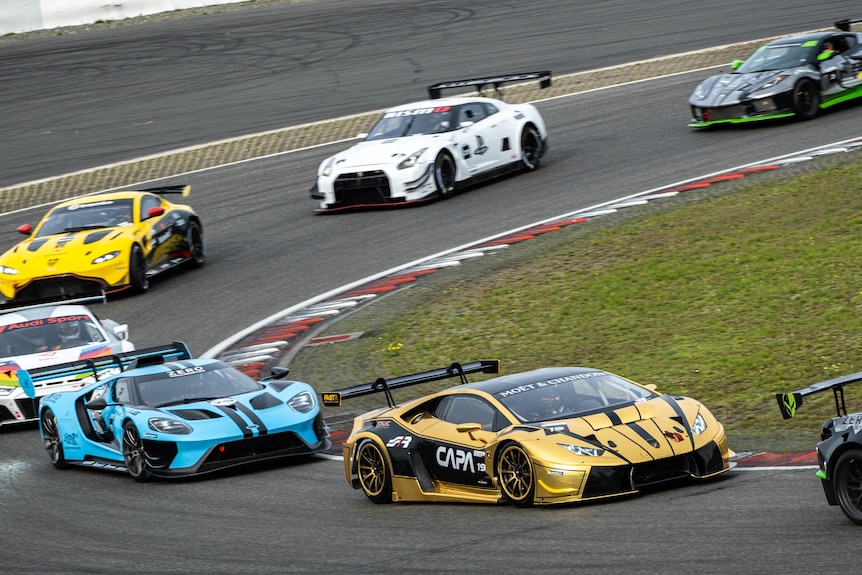 Professional racing cars taking a corner in a race.