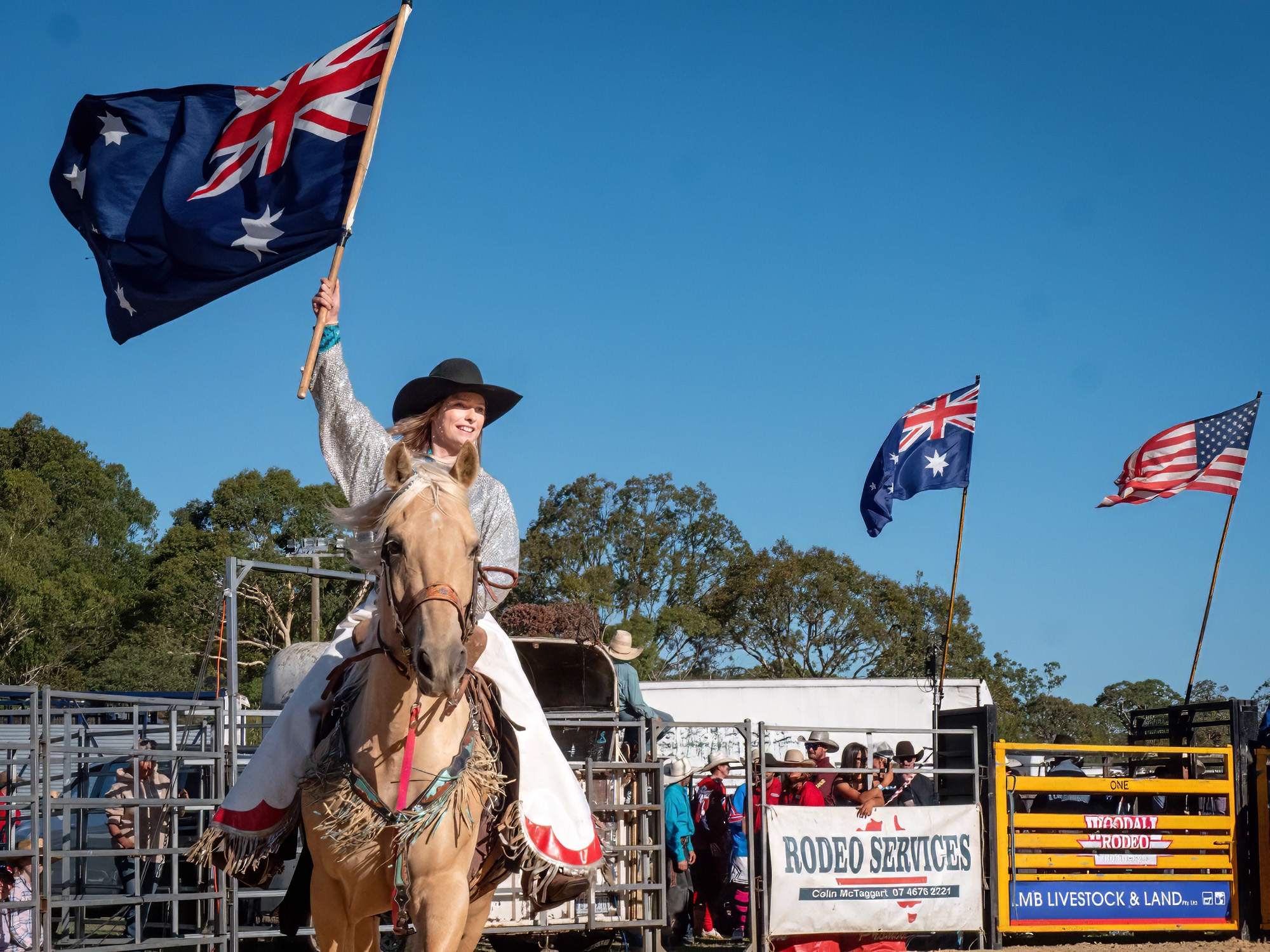 A woman riding a horse holding the Australian flag high. 