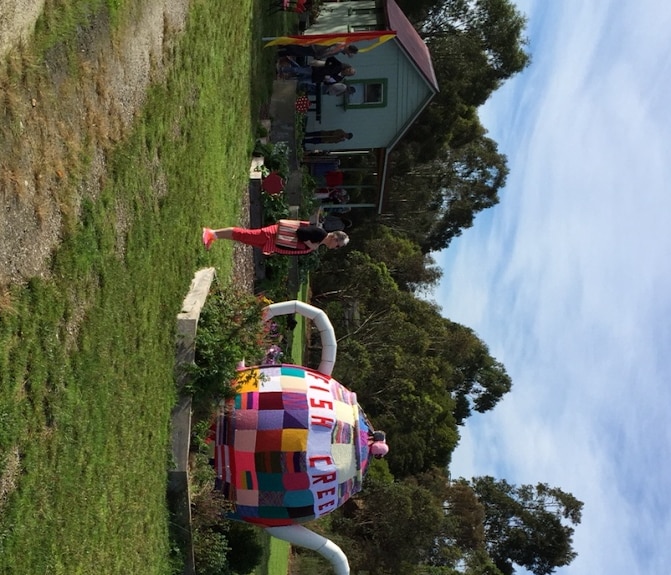 A giant tea pot that wears a tea cosy that says 'Fish Creek'.