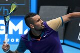 Tennis player Nick Kyrgios winds up to throw his broken racket off the court during a match.