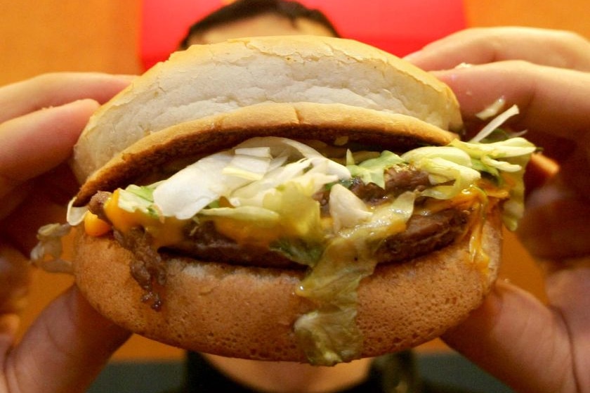 A young boy holds a hamburger.