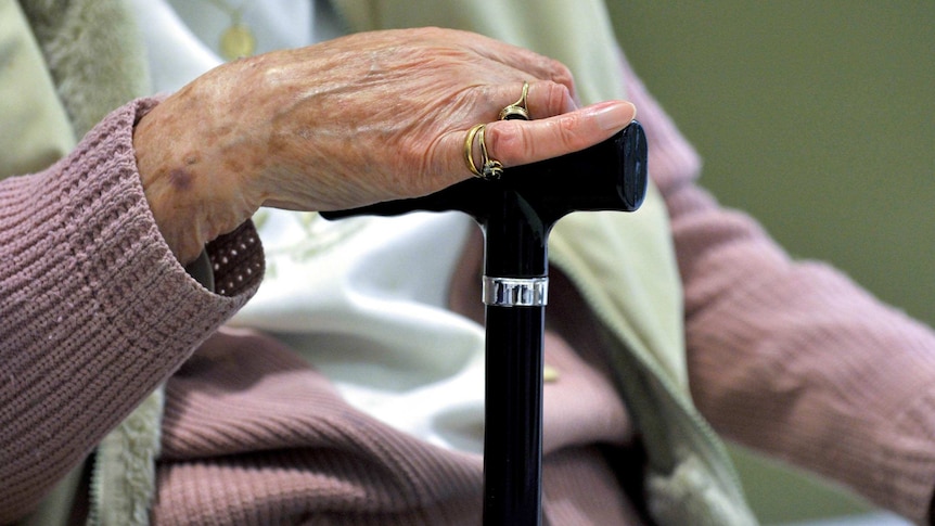 Elderly woman holding a walking stick.