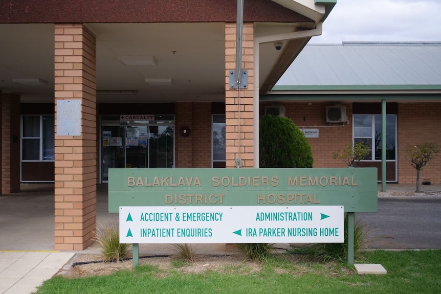 A directional sign outside a blonde brick building.