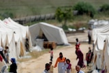Syrian refugees walk past tents at the Boynuyogun Turkish Red Crescent camp