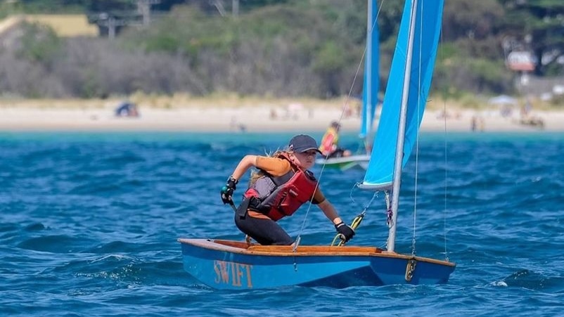 Young girl in small sailing boat on water.