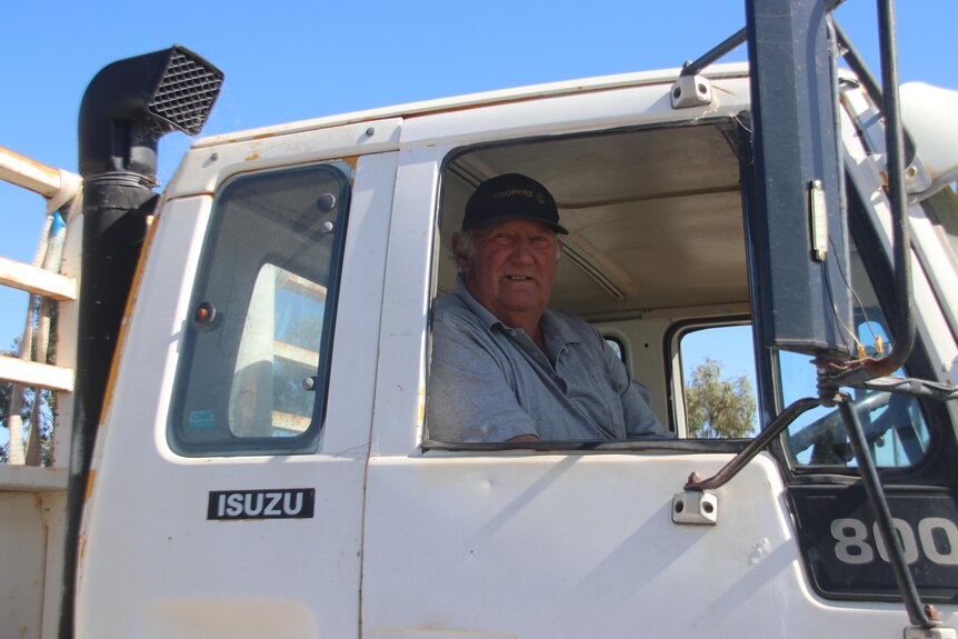 An elderly man in a hat and white truck 