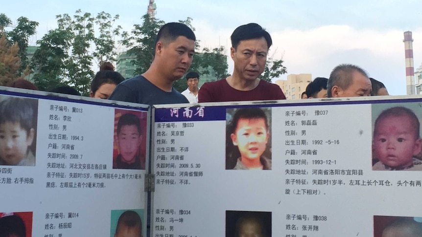 Passers by look at posters of missing children