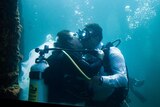 Mand and woman kissing underwater in full scuba gear.