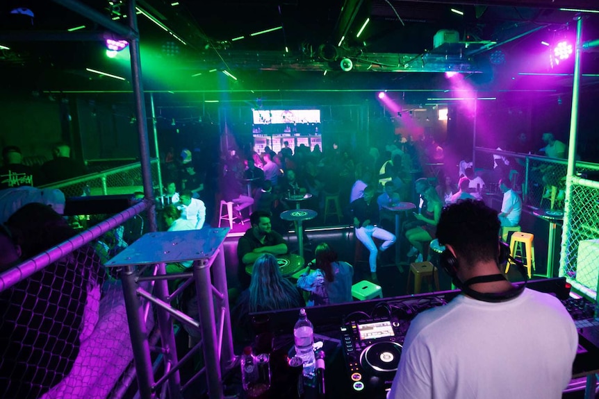 Inside a nightclub with green and purple lights.