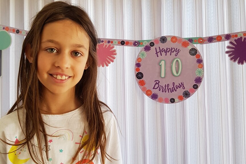 Mia Djurasovic standing in front of a happy 10th birthday sign