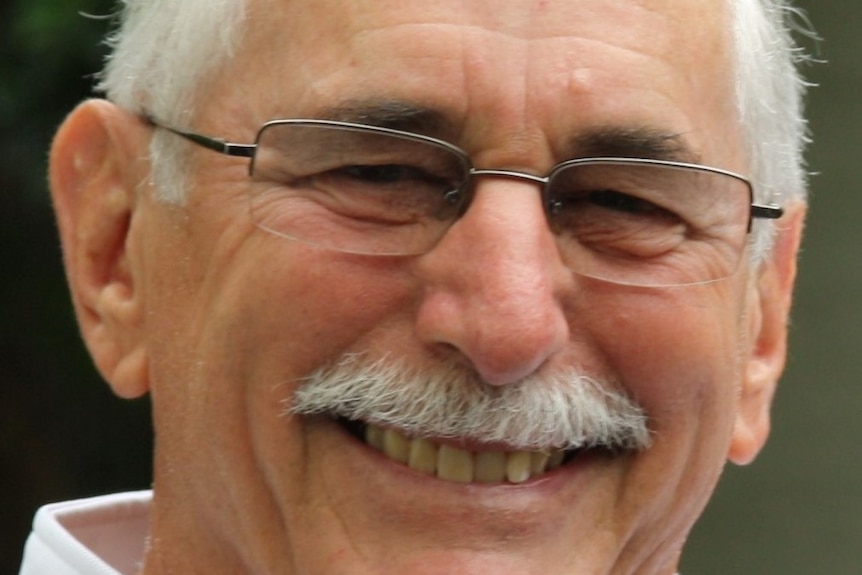 Smiling man, grey hair and glasses.