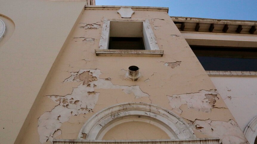Looking up at a building with paint peeling off it.