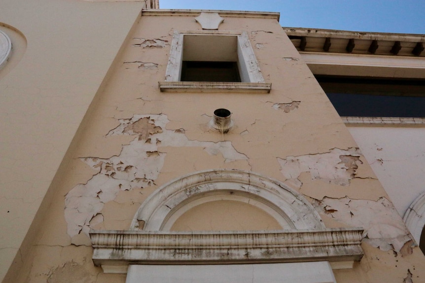 Looking up at a building with paint peeling off it.