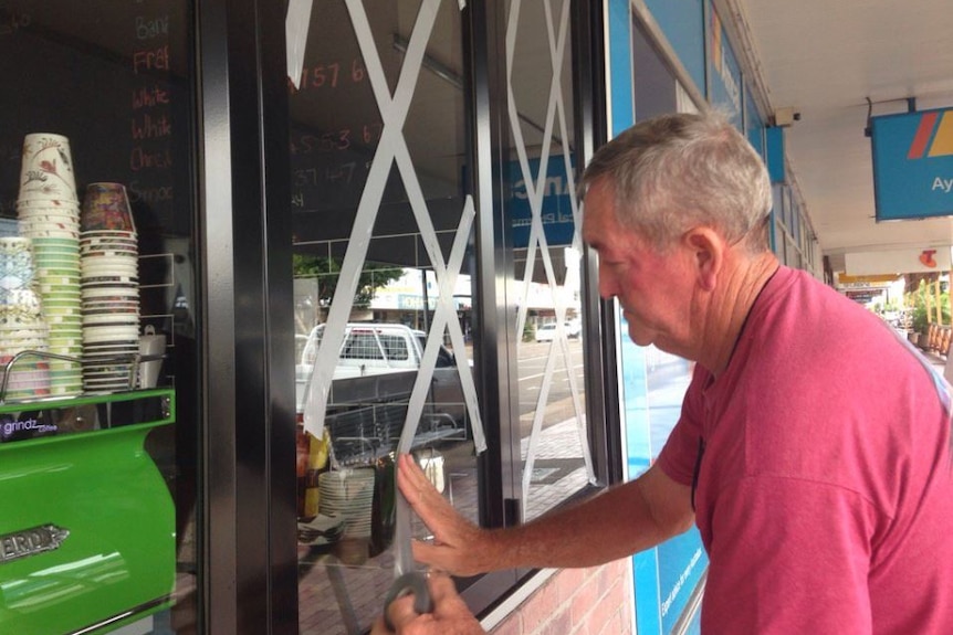 Shop owners up early in Ayr taping up windows and sandbagging ahead of Tropical Cyclone Debbie.