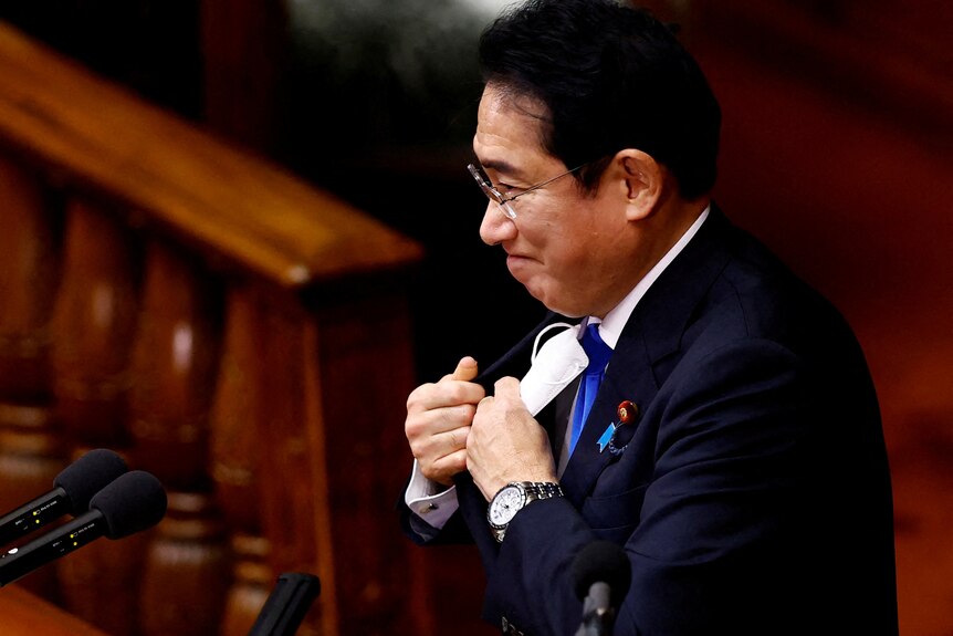 Fumio Kishida met un masque blanc dans sa poche avant de parler au parlement japonais