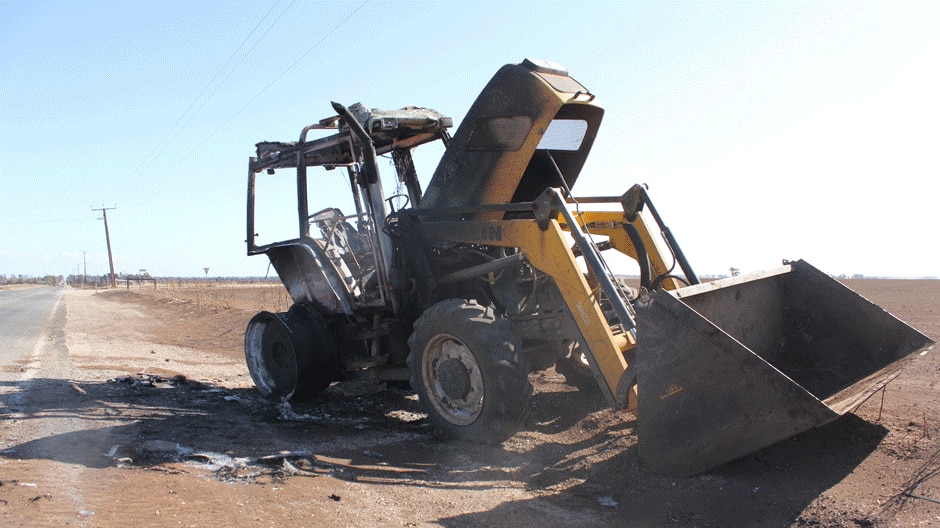 A burnt tractor sits abandoned