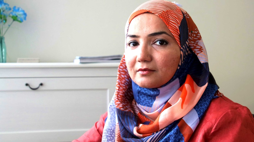 A woman in a headscarf stares at the camera.