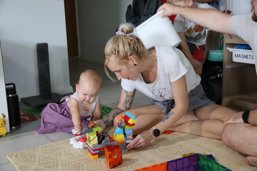 A woman plays with her daughter on the floor.