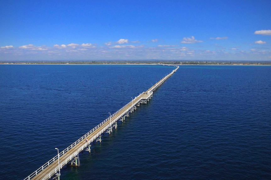 An aerial shot of a jetty extending far out from the coastline