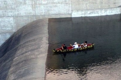 A canoe with several people inside approaches a downhill section of a dam