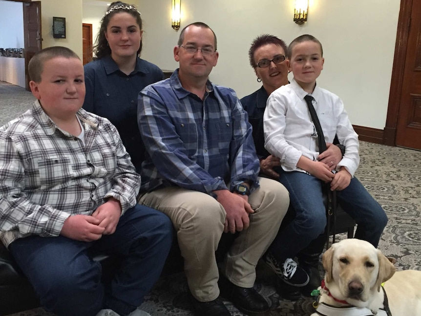 The Jones family sit together Petros the guide dog laying at their feet.