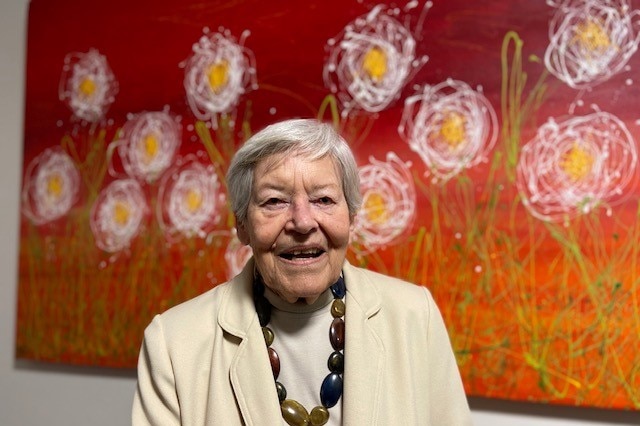 Dell Harrington smiles in front of a red painting.