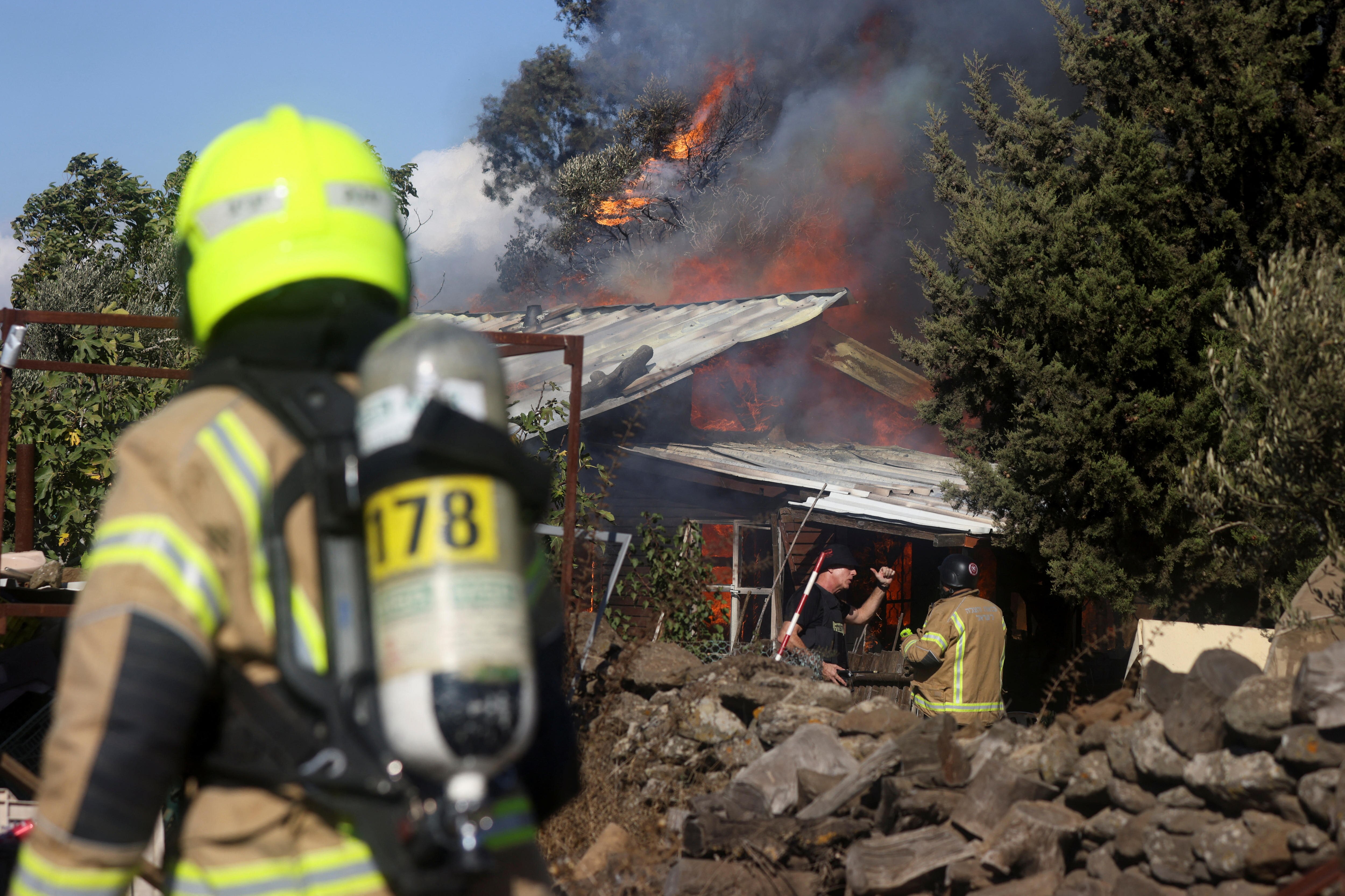 Two firefighters work to extinguish a blaze that has engulfed a house
