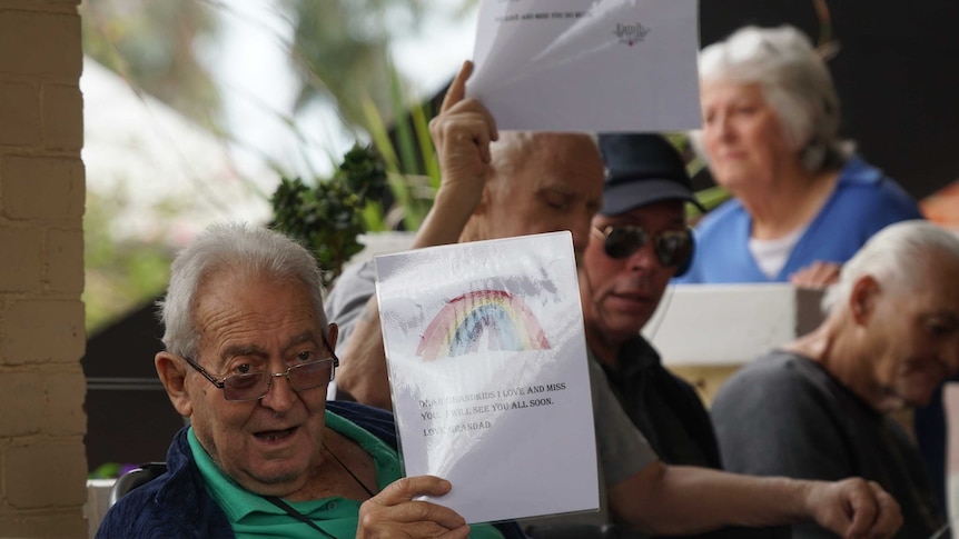 Group of older people hold up laminated messages to their families