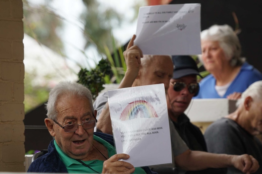Group of older people hold up laminated messages to their families