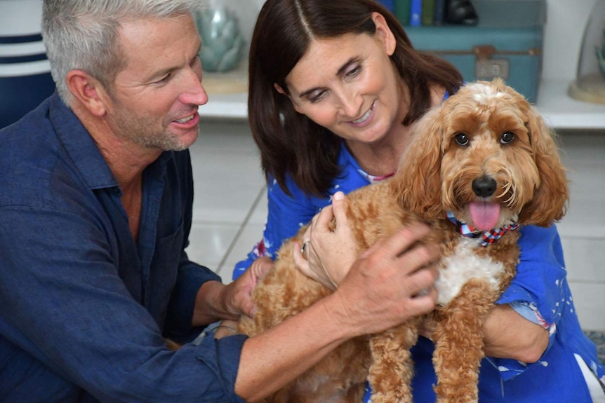 A man and a woman holding their pet dog