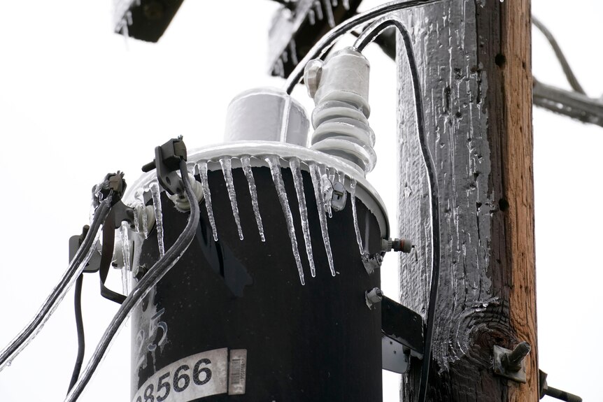 An electrical transformer is coated in ice and icicles in Dallas, Texas