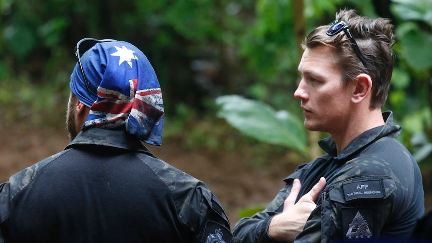 AFP personnel talk each other near a cave complex where 12 boys and their soccer coach went missing.