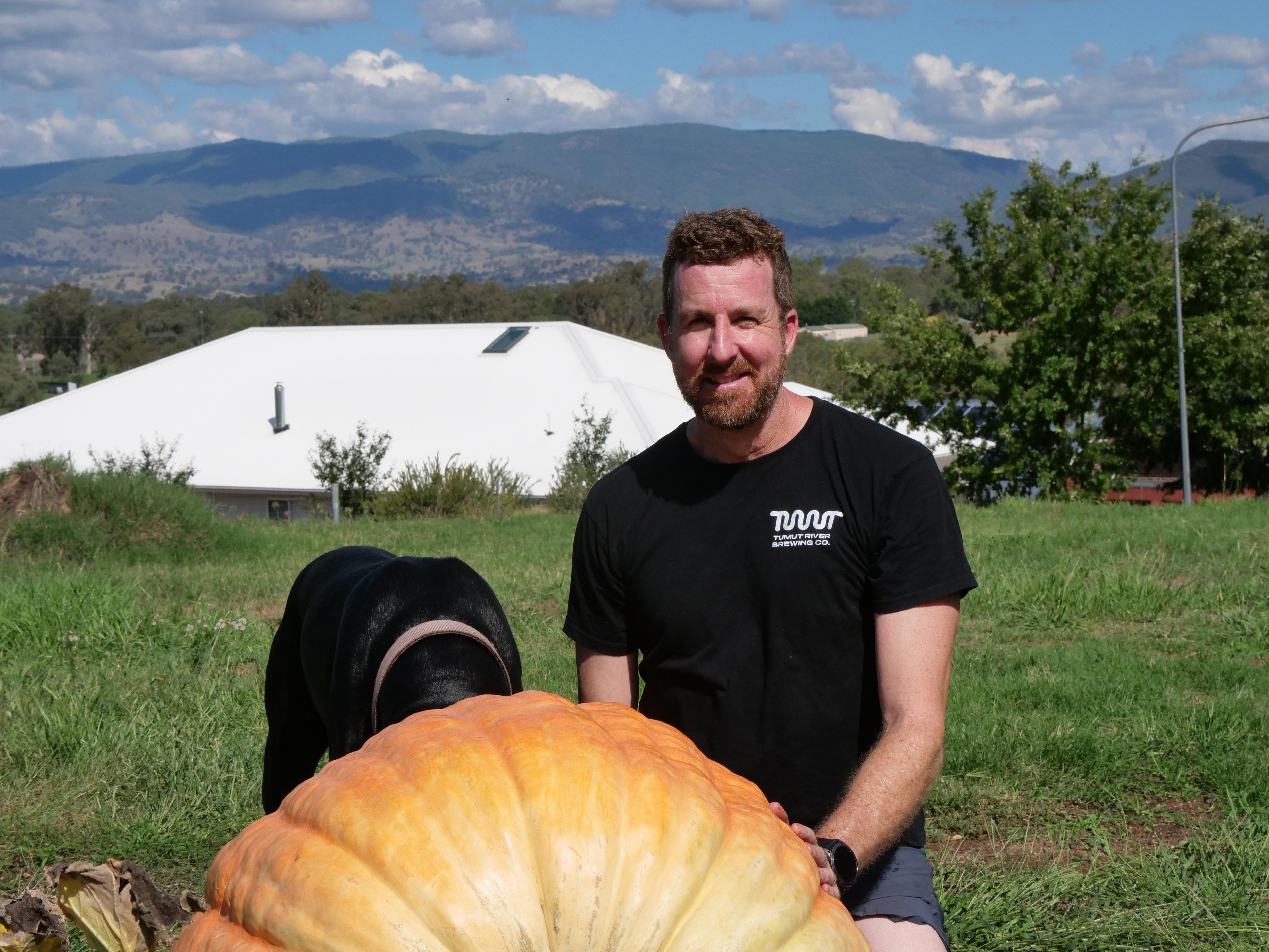 Hombre con camiseta negra y una calabaza en primer plano