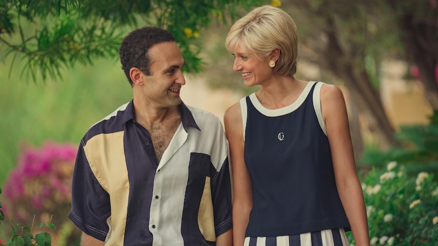 Khalid Abdalla wearing a button-up navy, white and yellow shirt, while Elizabeth Debicki wears a navy and white singlet