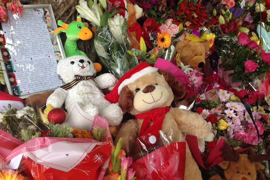 Teddy bears, notes and floral tributes left outside the Manoora house.