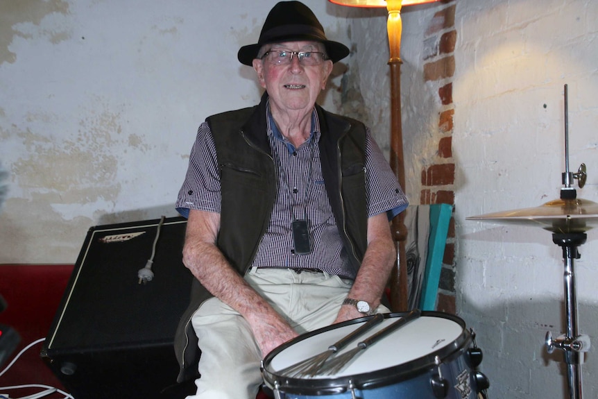 Hubert Davies wears a black hat while sitting at his drum kit.