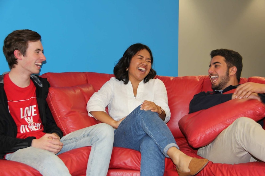Three people laughing on a lounge