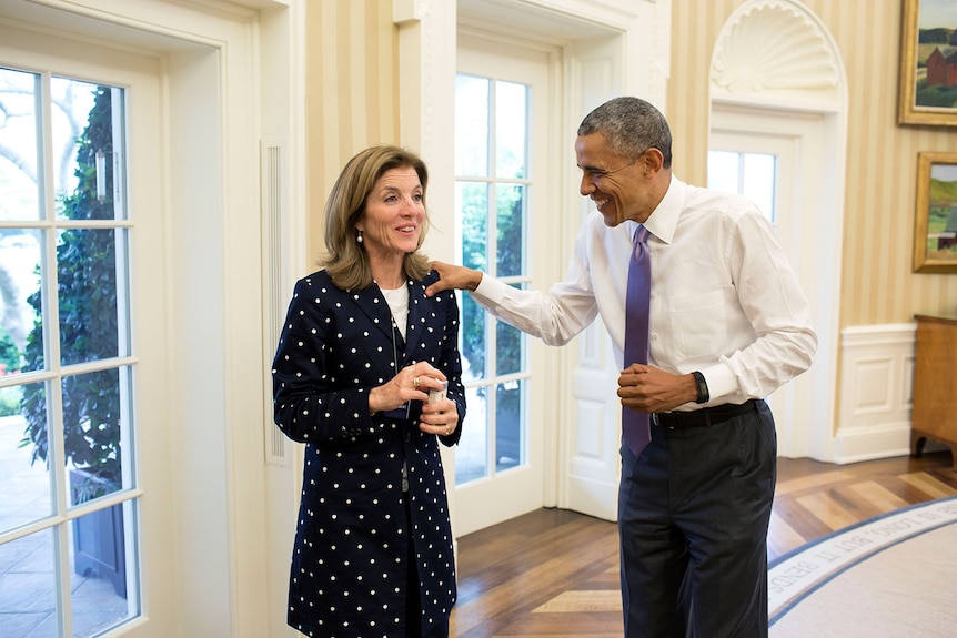 Barack Obama smiling and resting his hand on Caroline Kennedy's shoulder in the oval office