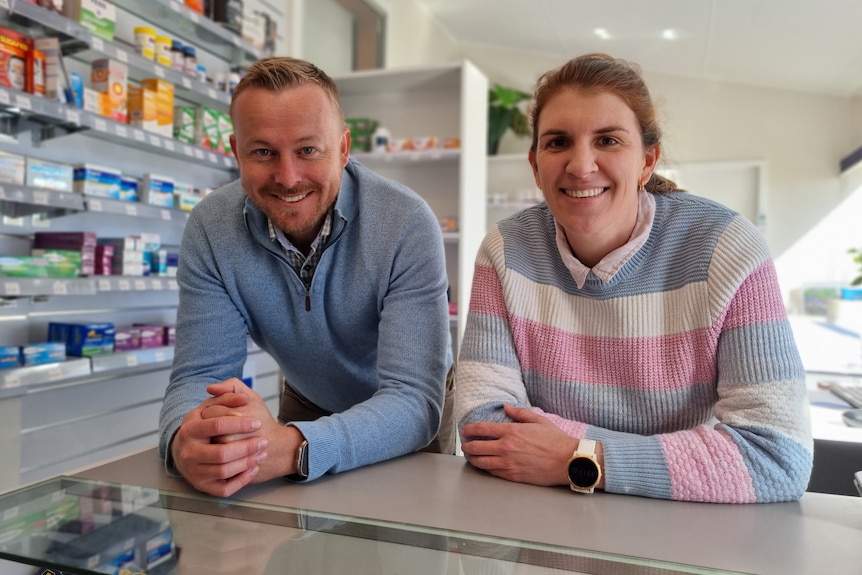 A man and women lean against a counter in a pharmacy.